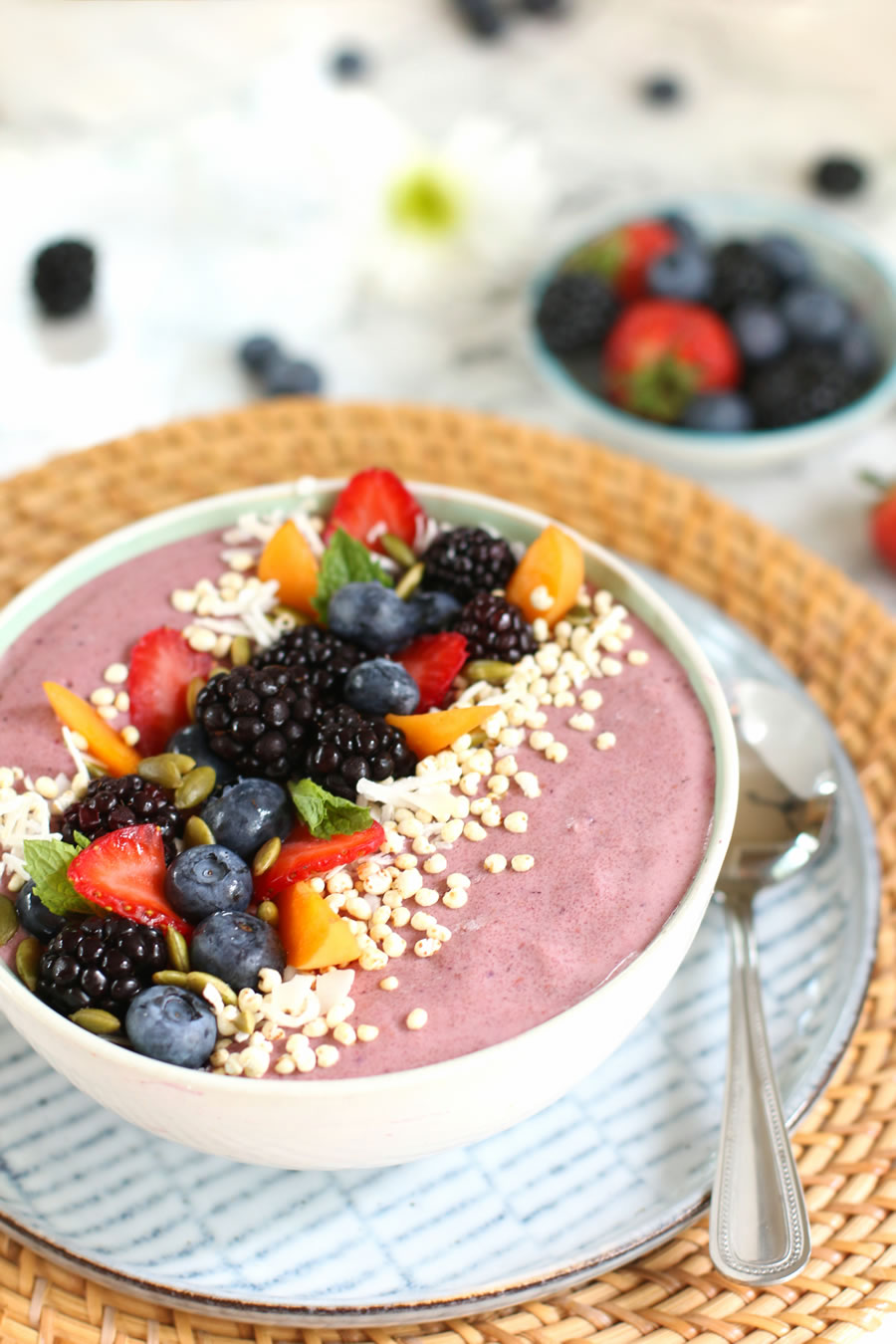 Anti-aging wrinkle reducing mixed berry and collagen peptide smoothie bowl topped with strawberries, blackberries, apricots, shredded coconut and pumpkin seeds.