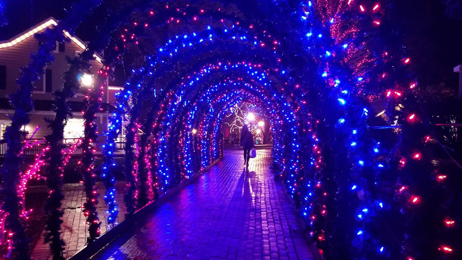 Woman walking with shopping bag under lights arch